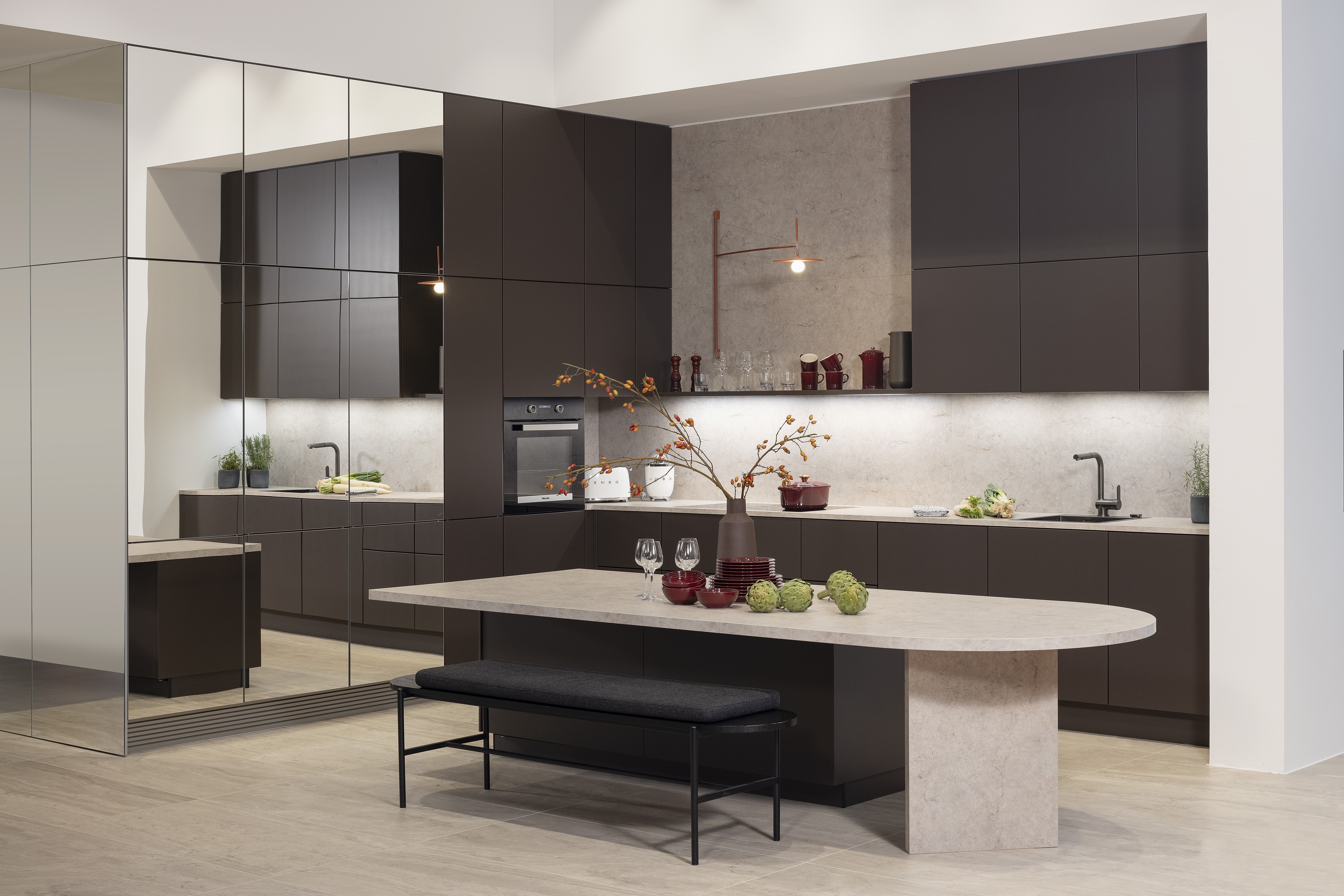 APL: Jura Beige Front: Soft Lack Sepiabraun softmatt Front: neoMirror Spiegel Korpus: Graphit Griff: PTO Geräte: Miele, Kochfeld elica Armatur: ? Spüle: Sternhagen   Features: Insellösung als Esstisch mit integrierten Unterschränken, Lichtboard über Arbeitsplatte, unterschiedliche Rastergrößen, Spielschränke für mehr Großzügigkeit, Nischenrückwand Wand hoch mit APL, ergonomischer Backofen, bedruckter Vinylboden in Steinoptik, komplette Planung PTO, Essentischlösung als zentraler Planungspunkt der Küche