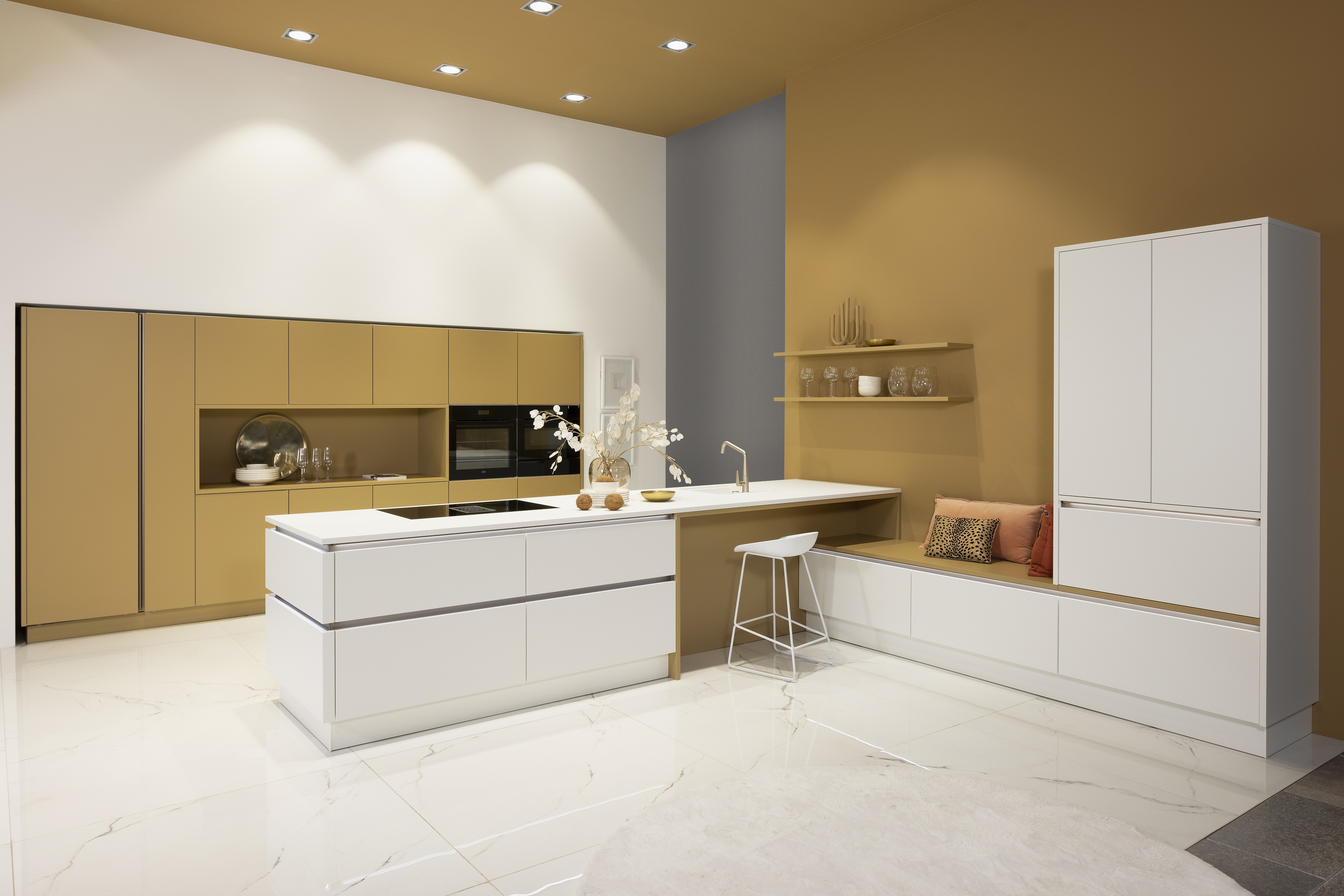 APL: Weiß Pro 25 mm Front: SoftLack Weiß softmatt Front: SoftLack Caramel softmatt Korpus: Weiß Griff: Kehlleiste Edelstahloptik, und PTO Geräte: AEG, Downdraft Faber Armatur: Gesi Spüle: elleci   Features: eingekoffertes Schrankelement mit integrierter Nische, Thema softmatt, Kompaktbackofen mit Wärmeschublade, Griffleiste beleuchtet, durchgehende Linienführung an Insellösung, Wandfarbe in Caramel wie Frontfarbe, Regale in Frontfarbe, Sitzbank mit Unterschränken, Marmorfliesenboden.